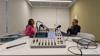 a man and woman sitting at a table with a microphone